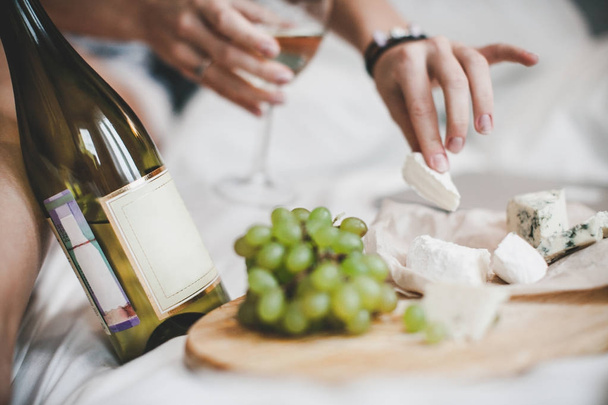 Uvas y botella de vino blanco con plato de queso para el almuerzo en el dormitorio
.  - Foto, Imagen