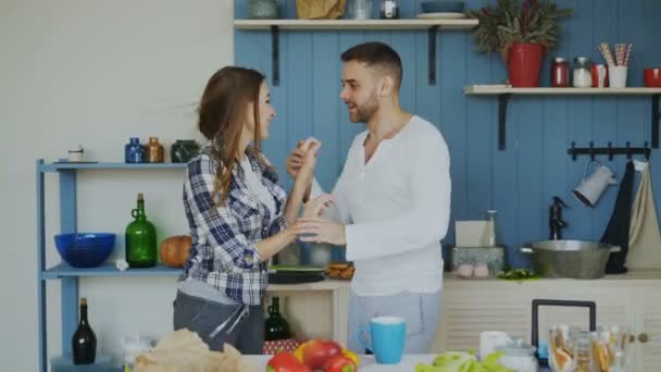 Cheerful and attractive young couple in love dancing together latin dance in the kitchen at home on holidays - Felvétel, videó