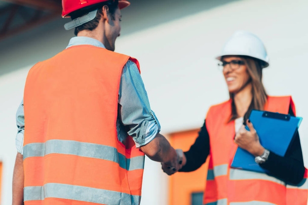 Business people handshaking on construction site - 写真・画像