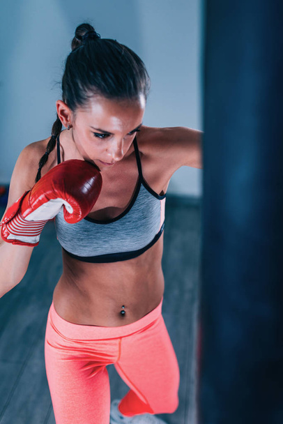 Mujer joven haciendo ejercicio en el gimnasio en el saco de boxeo
 - Foto, Imagen