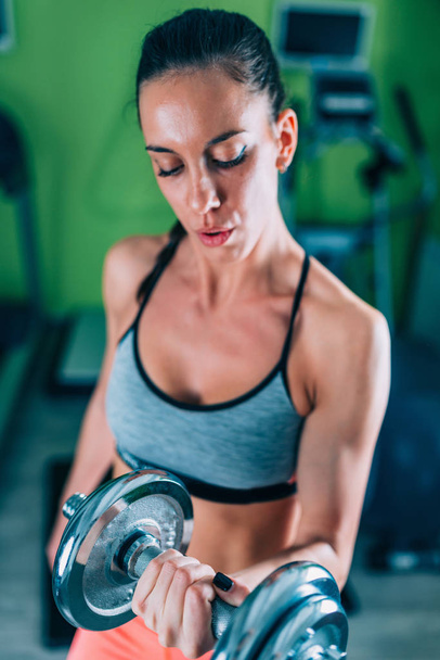 Genç kadın spor salonunda ağırlık egzersiz - Fotoğraf, Görsel