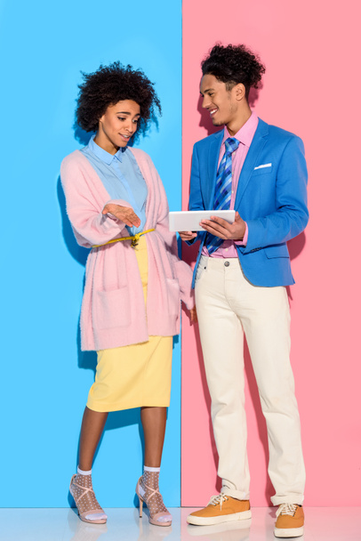 Happy couple using digital tablet on pink and blue background  - Fotografie, Obrázek