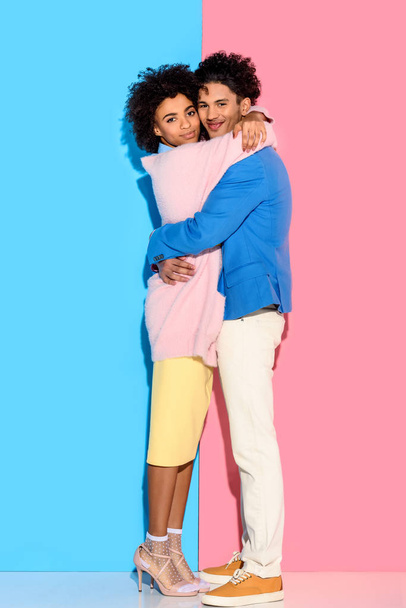 fiatal pár átölelte egymást a rózsaszín és a kék háttér   - Fotó, kép