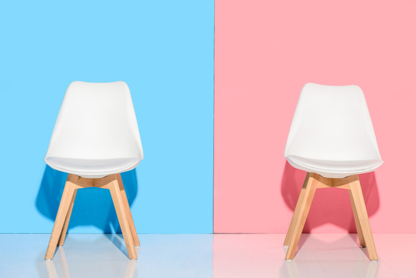 close up view of white chairs against blue and pink wall - 写真・画像