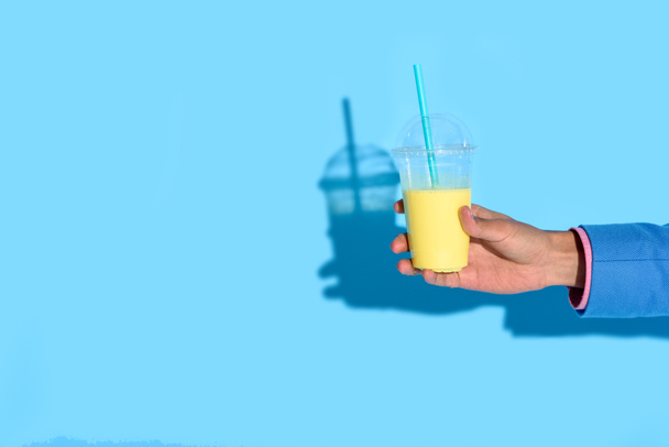 Cropped shot of african american man holding glass of juice on blue background - Photo, image