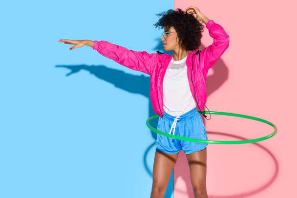 Sportos nő pózolt a karika rózsaszín és kék a háttér exersizing  - Fotó, kép