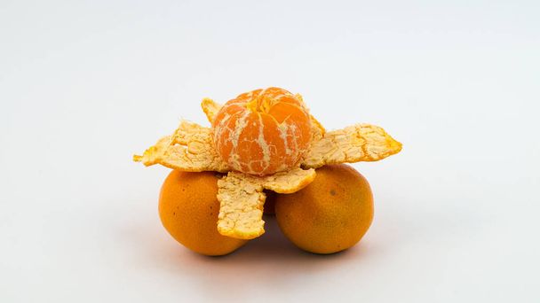Three mandarins, on which one another with skin removed. - Fotoğraf, Görsel