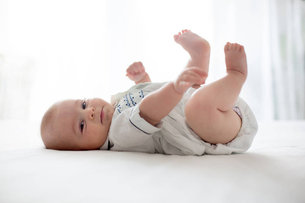 Cute little four month old baby boy, playing at home in bed - Foto, Imagem