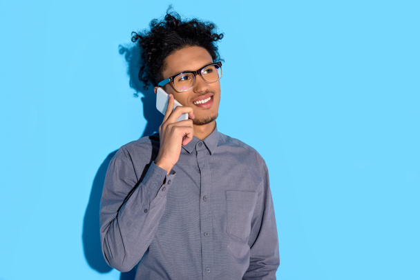 Young african amercian businessman talking on phone on blue background  - Foto, Imagem