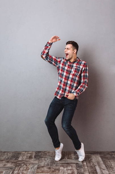 Full-length image of Screaming happy man in shirt and jeans - Фото, зображення