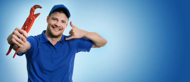 plumbing services - plumber with wrench showing phone call gesture on blue background with copy space - Photo, Image