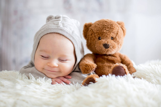 Sweet baby boy in bear overall, sleeping in bed with teddy bear - Fotoğraf, Görsel
