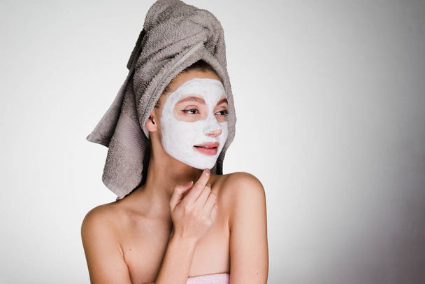 attractive girl with a towel on her head, on her face a useful white mask - Фото, зображення