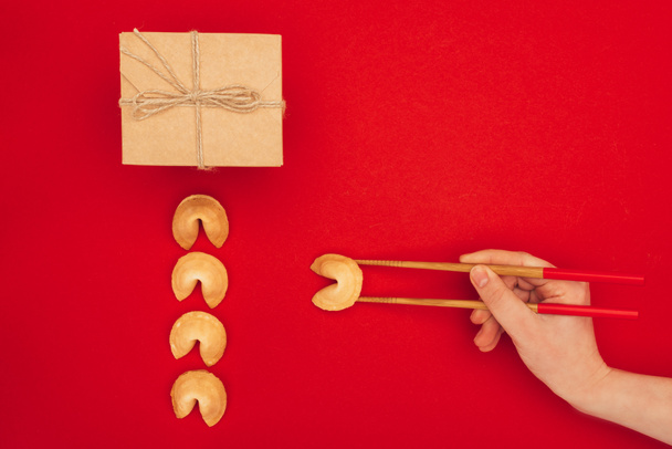 cropped shot of woman taking chinese fortune cookie with chopsticks, Chinese New Year concept - Photo, Image