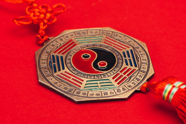 close-up shot van traditionele Chinese yin en yang talisman op rood oppervlak - Foto, afbeelding