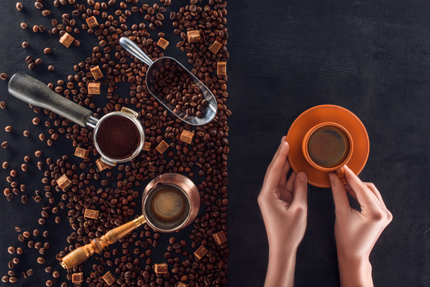 一杯のコーヒーとコーヒー ポット、スクープ砂糖とコーヒー豆の焙煎を保持している人の部分のトップ ビュー  - 写真・画像