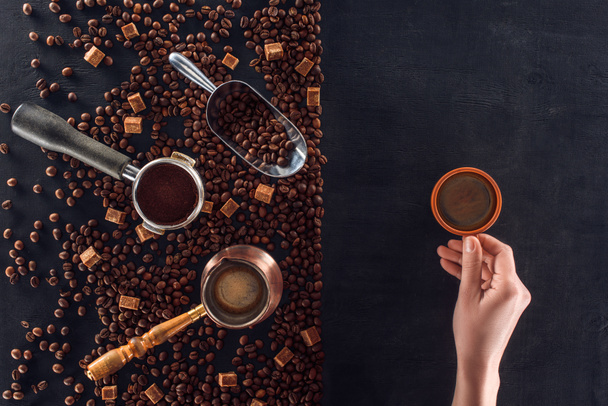 一杯のコーヒーとコーヒー ポット、スクープ砂糖とコーヒー豆の焙煎を保持している人の部分的なビュー  - 写真・画像
