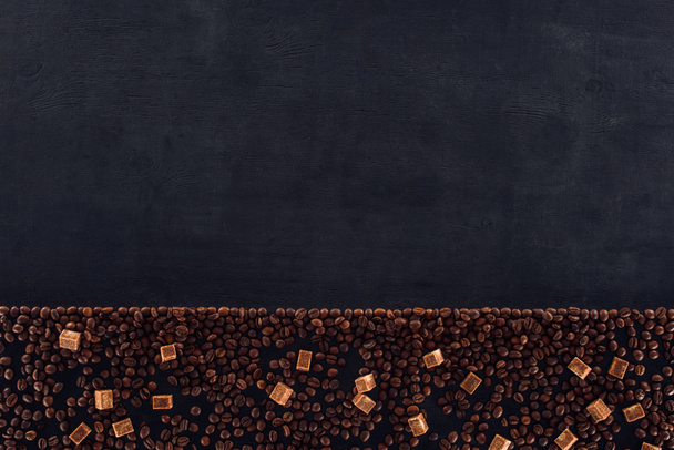 верхний вид жареных кофейных зерен с коричневым сахаром на черном
 - Фото, изображение