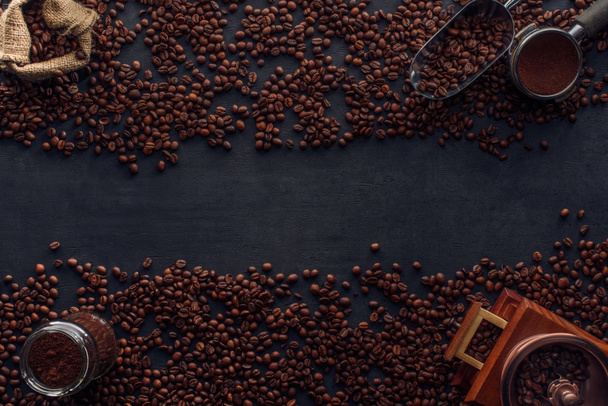 vista superior de grãos de café torrados, pano de saco, moedor de café e colher em preto
 - Foto, Imagem