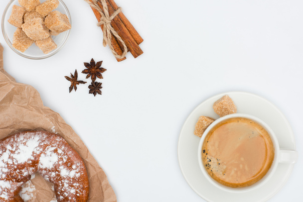 vue du dessus de tasse de café avec soucoupe et cassonade, pâtisserie, étoiles d'anis et bâtonnets de cannelle attachés avec une corde isolée sur blanc
  - Photo, image