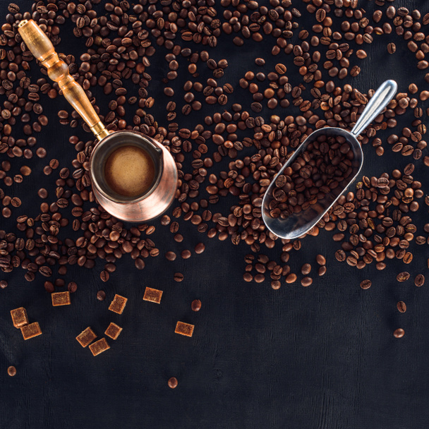 vista superior de granos de café tostados, cucharada y cafetera en negro
 - Foto, Imagen