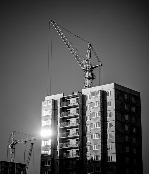 silhouettes of industrial construction cranes and building - Photo, Image