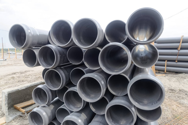 Avvicinamento di tubi in gomma su pali e altri materiali e attrezzature da costruzione in cantiere
 - Foto, immagini