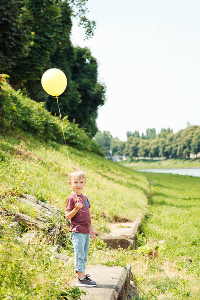 Pouco engraçado menino jogar com balão amarelo ao ar livre
. - Foto, Imagem