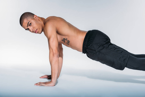 african american sportive man doing push up and looking at camera - Foto, afbeelding