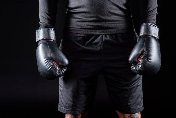 tiro recortado de boxeador en guantes negros aislados en negro
 - Foto, Imagen