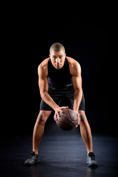concentrated african american basketball player with ball on black - Foto, imagen