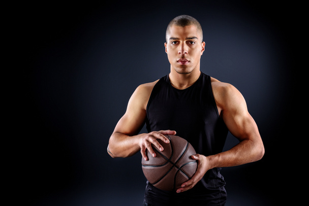 handsome african american basketball player with ball isolated on black - Foto, Imagen