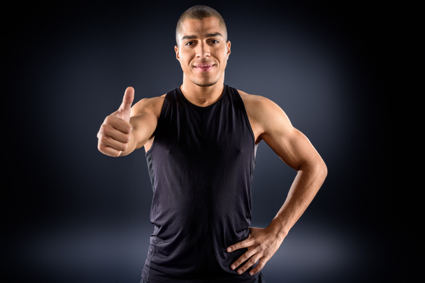 handsome african american sportsman showing thumb up on black - Foto, afbeelding
