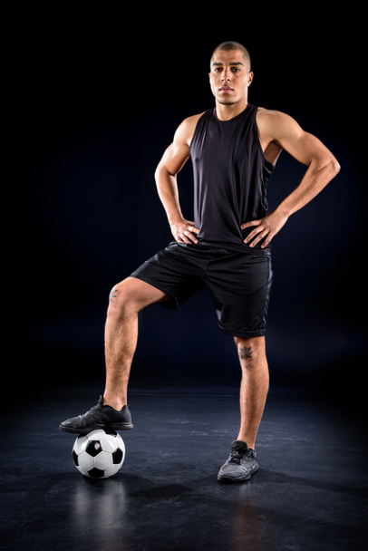 handsome african american soccer player standing with ball on black - Photo, Image