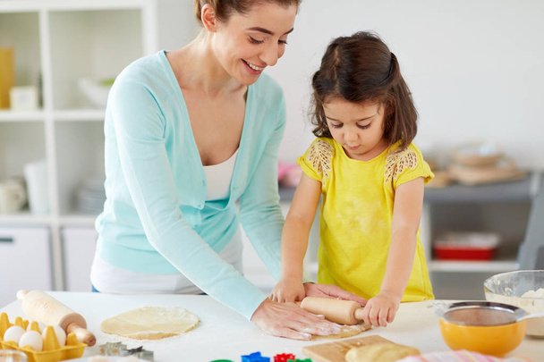 happy mother and daughter making cookies at home - Fotó, kép