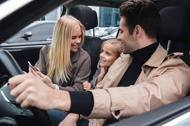 Χαρούμενος άνθρωπος που κάθεται στο αυτοκίνητο με τη γυναίκα και την κόρη - Φωτογραφία, εικόνα
