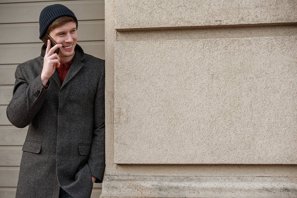 Cheerful young man talking on phone and smiling - Photo, image