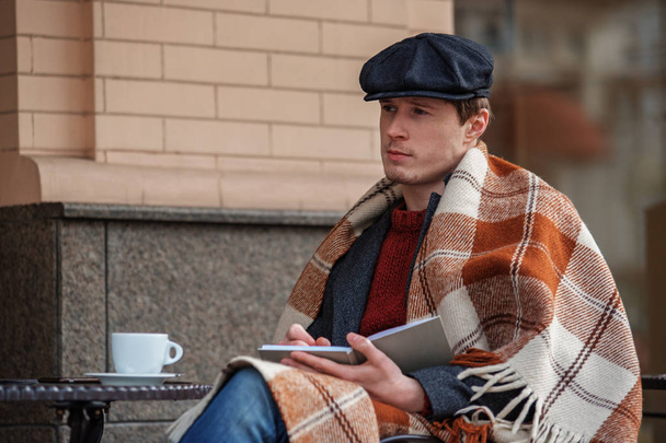 Pensive creative man sitting at table and holding notebook - Valokuva, kuva