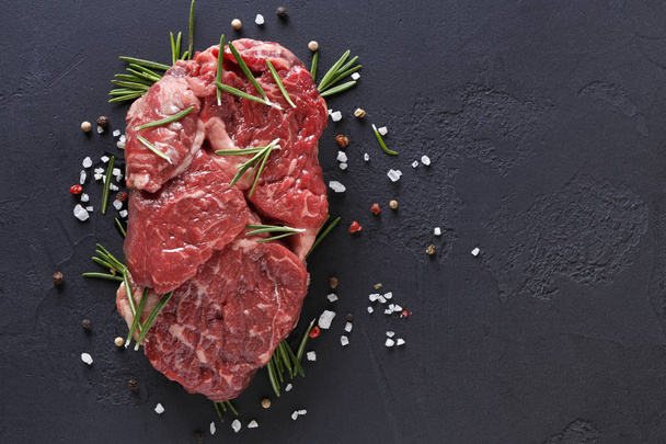 Rib eye steak, kruiden en groenten op zwarte achtergrond - Foto, afbeelding
