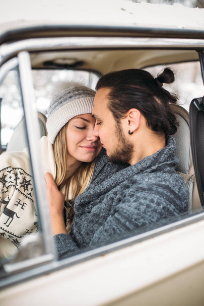 Handsome hipster Man and beauty woman kiss each other sitting in the retro car . Valintines Day concept. Vertical picture - Фото, изображение