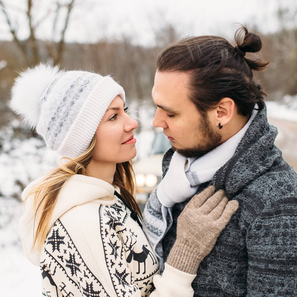 winter snow couple love story.Beautiful girl in cozy hat and handsome bearded man hugs each other. pullover with traditional winter ornament. Square picture - Valokuva, kuva