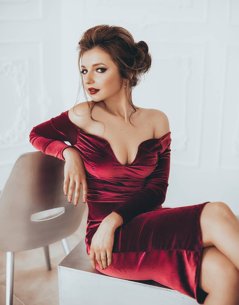 Beautiful young woman   posing in red,velvet dress in studio - Foto, imagen