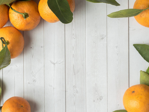 Fresh mandarin or tangerines with stems and leaves on white wooden background Copy space - Foto, Imagem