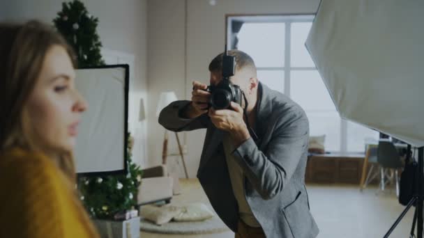 Professional photographer man taking photo of beautiful model girl with digital camera in studio - Materiaali, video