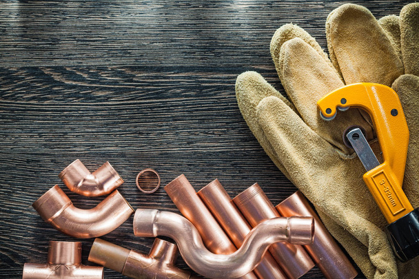 Plumbing brassware pipe cutter safety gloves on wooden board - Fotó, kép
