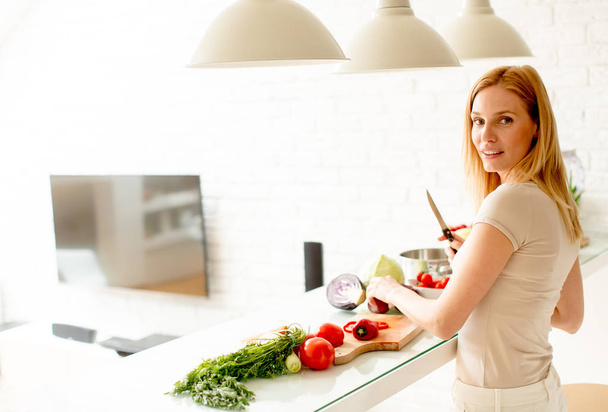 Pretty young woman preparing healthy meal in the kitchen - Foto, imagen