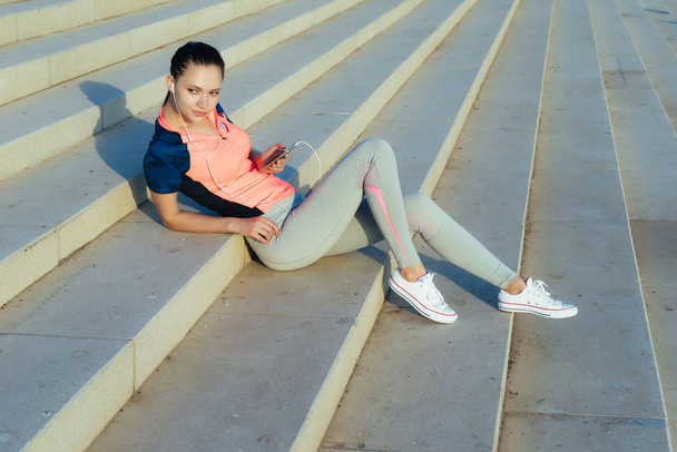 young girl in a sports suit is lying on the steps in the park - Foto, immagini