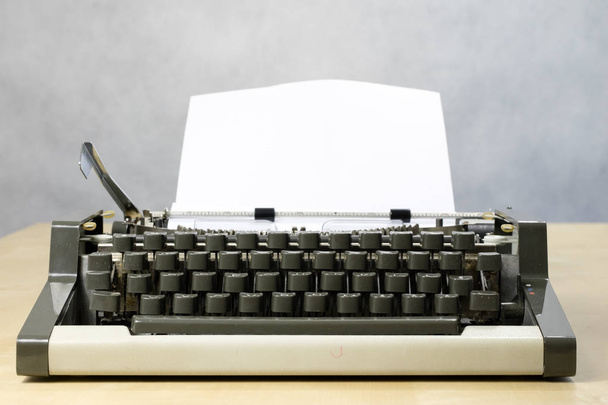 Typewriter and white card screwed into the machine. Wooden table - Valokuva, kuva