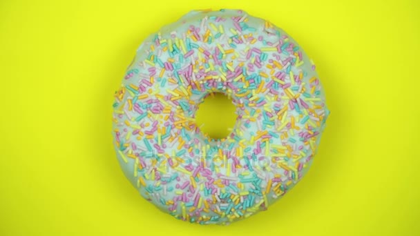 おいしい甘いドーナツ プレートを回転させます。平面図です。明るくカラフルな振りかけたドーナツ クローズ アップ マクロは、黄色の背景に回転を撮影. - 映像、動画