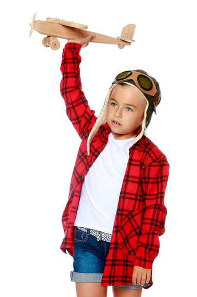 Κοριτσάκι με ένα ξύλινο αεροπλάνο στο χέρι. - Φωτογραφία, εικόνα
